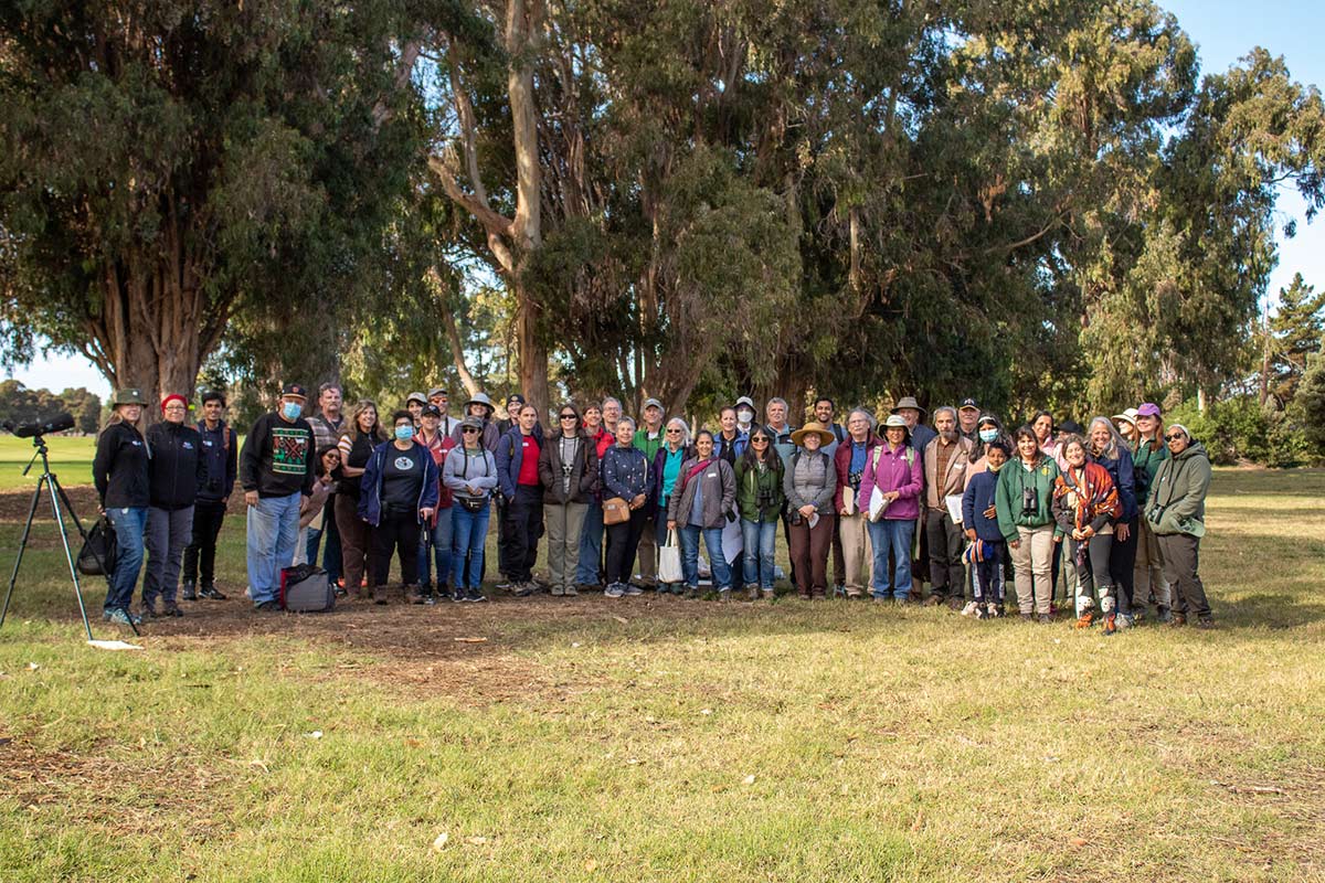 Many volunteers posting for a photo in front of trees