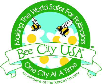 The Bee City USA logo, which has a dark green circle around a stylized scene with bees and white flowers. A banner across it says 