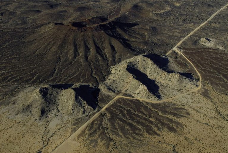Hilly terrain interrupts the landscape of the proposed border wall, as seen from above.