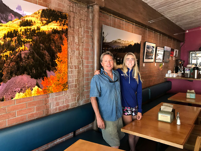 Soleil and Lucas Price, owner and chef at La Cocina de Luz, in front of the photo exhibit at the restaurant. Photo by Maile McCann/Telluride Daily Planet; used with permission