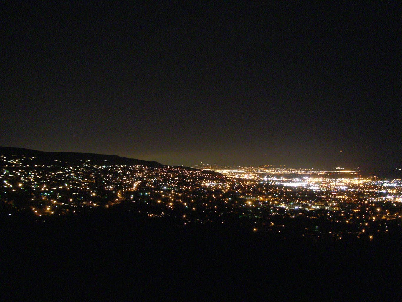 A city's light creates a bright glow in an otherwise-dark scene.