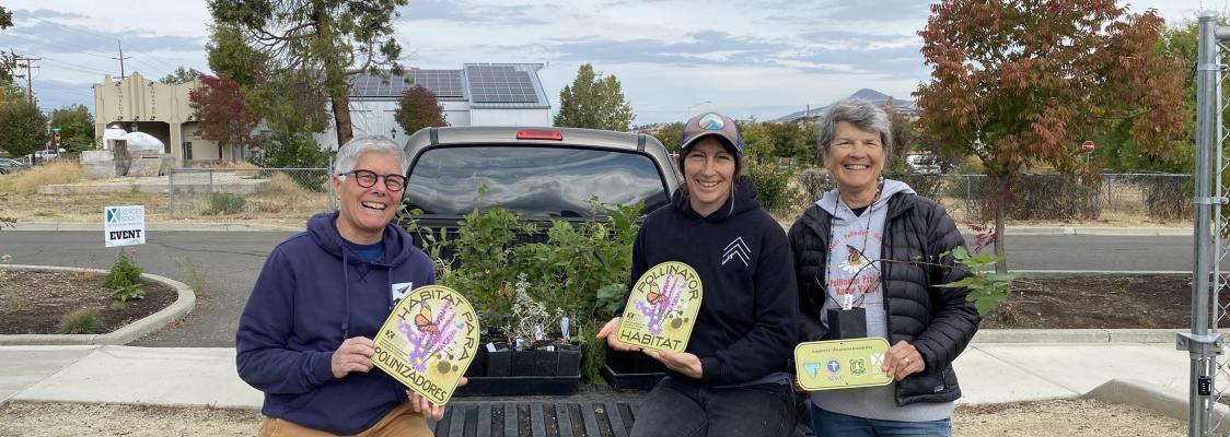 Three Habitat Kit participants with plants and pollinator habitat signs at OR distribution day. 