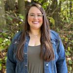 Kailee Slusser standing in front of a wooded area